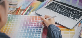 Designer gráfico escolhendo uma cor de uma paleta cromática enquanto trabalha no computador