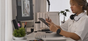 Designer gráfico desenhando em uma mesa digitalizadora com uma caneta stylus, trabalhando em um projeto criativo