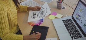 Designer gráfico desenhando em uma mesa digitalizadora com uma caneta stylus, trabalhando em um projeto criativo